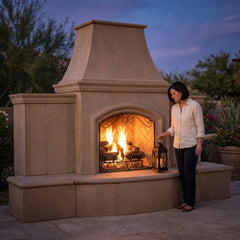 Woman beside the 87-inch-tall American Fyre Designs Grand Phoenix outdoor fireplace at dusk