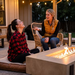 Two friends around the AFD Iron Saddle fire table at dusk