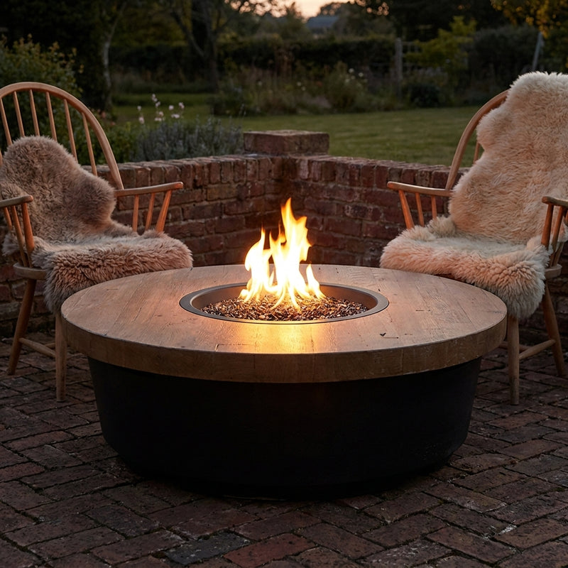 AFD Reclaimed Wood Contempo Round fire table burning in a walled garden at dusk