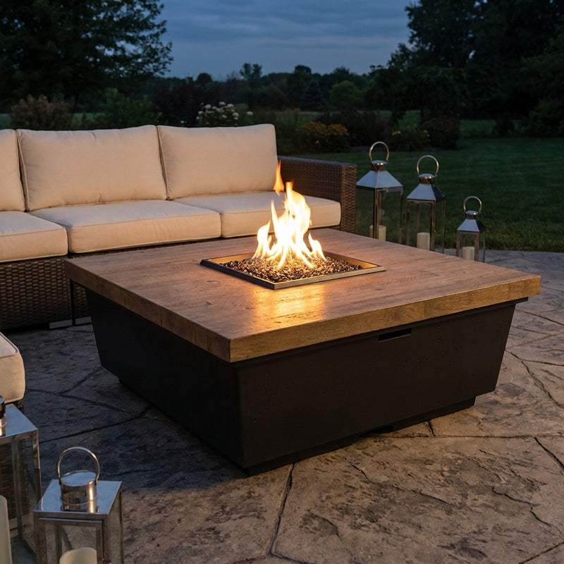AFD Reclaimed Wood Contempo Square fire table burning on a stone patio at dusk