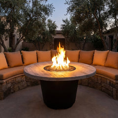 AFD Reclaimed Wood Cosmopolitan Round fire table burning in a courtyard at dusk