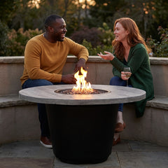 Two friends around the AFD Cosmopolitan Round fire table at dusk