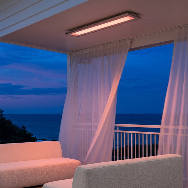 Bromic Platinum Smart-Heat Electric 4500W white panel glowing on a coastal veranda at dusk