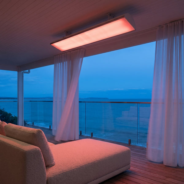 Bromic Platinum Smart-Heat Electric 4500W white panel surface-mounted under a coastal veranda soffit at dusk