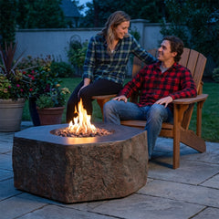 Couple beside the 16-inch-tall Elementi Columbia boulder fire table at dusk