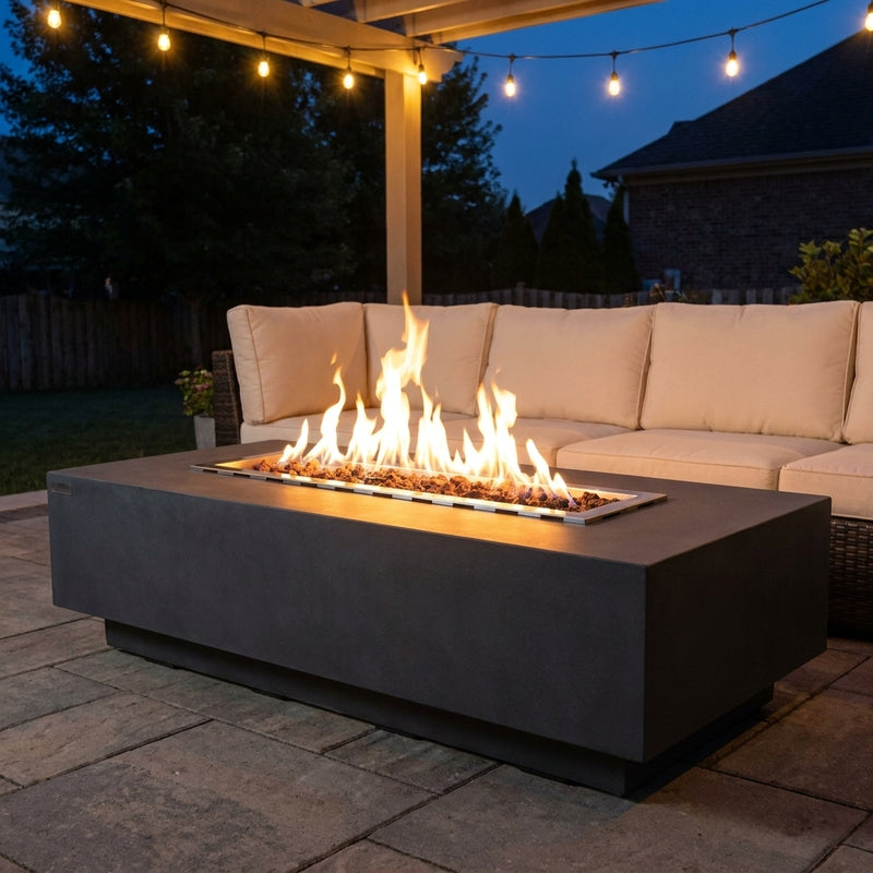 Elementi Granville fire pit table with flames lit on an evening patio in front of an outdoor sectional