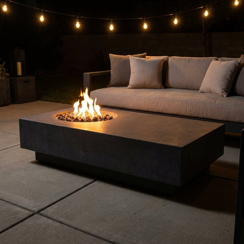 Elementi Metropolis low rectangular fire pit table in dark gray with flames lit on an evening patio
