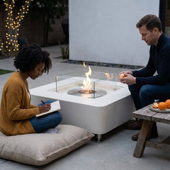 Two people relaxing beside the 14-inch-tall Elementi Perth ethanol fire table at dusk