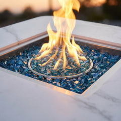Close-up of the round flame over Caribbean blue fire glass in the Elementi Plus Annecy