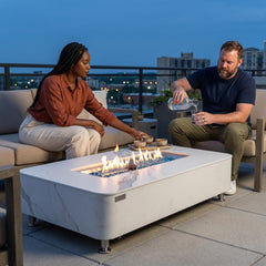 Two people relaxing beside the 14-inch-tall Elementi Plus Athens porcelain fire table at dusk