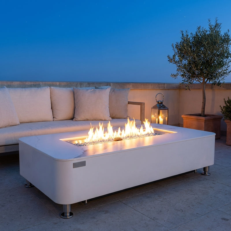 Elementi Plus Athens white porcelain fire table with linear flame over Caribbean blue fire glass on a rooftop terrace at dusk