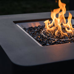 Close-up of flames over dark fire glass in the Elementi Plus Bergamo square concrete fire pit table
