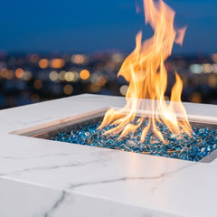 Close-up of flames over Caribbean blue fire glass in the white marble porcelain Bianco