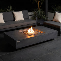 Elementi Plus Cannes dark charcoal fire table with a square burner recess and bronze fire glass on a modern patio at night