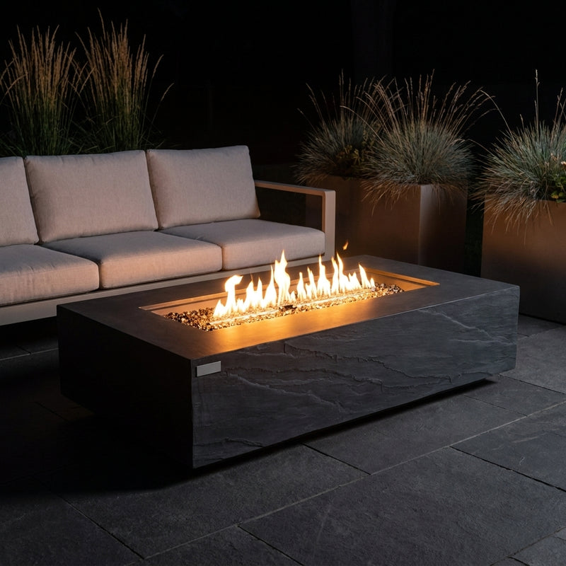 Elementi Plus Cape Town slate black sandstone fire table with linear flame over bronze fire glass on a stone patio at night