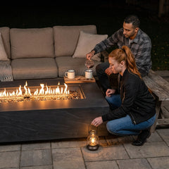 Two people settling in beside the 15-inch-tall Elementi Plus Cape Town fire table at night