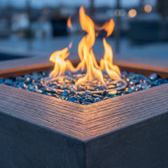 Close-up of flames over Caribbean blue fire glass and striated texture on the Elementi Plus Capertee fire pit table
