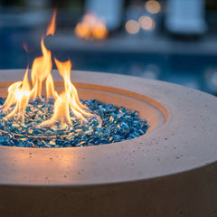 Close-up of flames over Caribbean blue fire glass in the Elementi Plus Colosseo concrete fire pit table