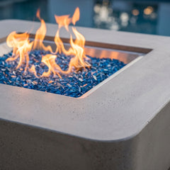Close-up of flames over Caribbean blue fire glass in the Elementi Plus Lucerne square concrete fire pit table