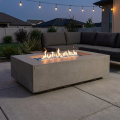 Elementi Plus Meteora space gray sandstone fire table with linear flame on a modern patio at dusk