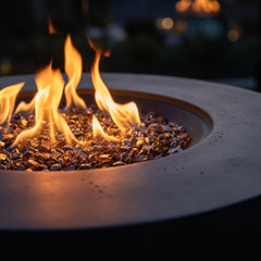 Close-up of flames over bronze fire glass in the Elementi Plus Nimes concrete fire pit table