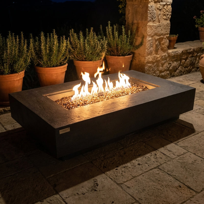 Elementi Plus Positano dark gray sandstone fire table with flames over bronze fire glass at night