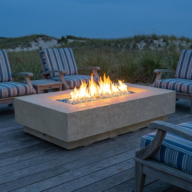 Elementi Plus Riviera light gray sandstone fire table with linear flame on a coastal deck at dusk