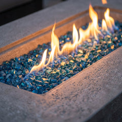 Close-up of flames over Caribbean blue fire glass in the light gray sandstone Elementi Plus Riviera