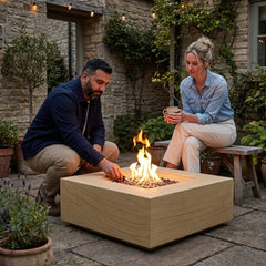 Two people around the shin-height Elementi Plus Uluru sandstone fire pit table at dusk