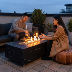 A couple having tea beside the 17-inch-tall Elementi Plus Varna porcelain fire table at dusk