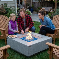 Family toasting marshmallows around the seat-height Elementi Plus Victoria square fire table at dusk