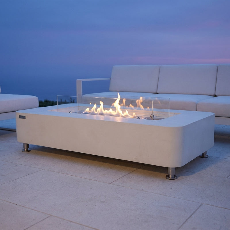 Cream white Elementi Sydney ethanol fire table with linear flame and glass wind panels at dusk