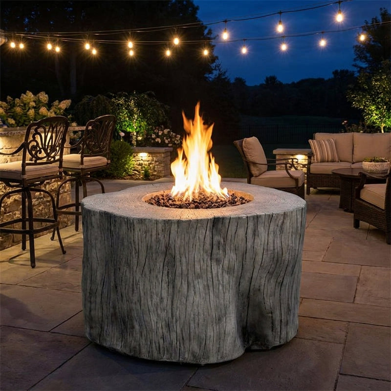 Elementi Warren chat-height tree-stump fire pit table in Gray with flames lit on an evening patio