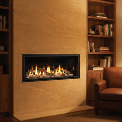 Majestic Echelon II 36 linear direct vent gas fireplace in a limestone study wall, burning at evening