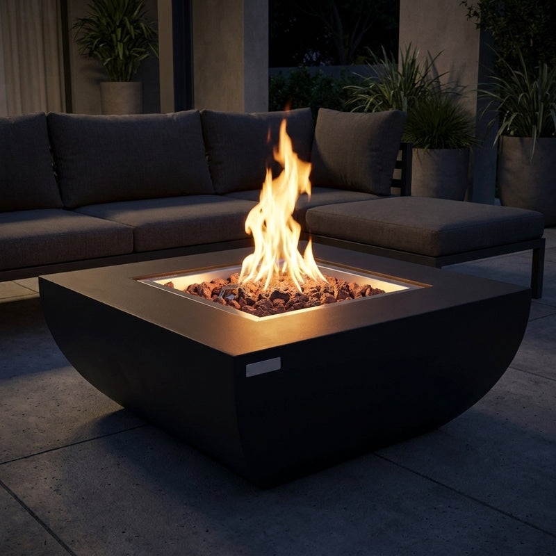 Black Modeno Aurora curved concrete fire pit table with flames over lava rock at night