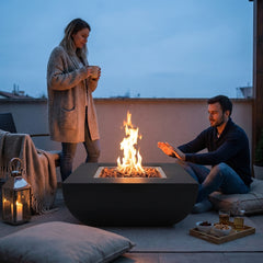 Two people beside the 14-inch-tall Modeno Aurora fire pit at dusk