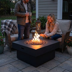 Two people beside the 17-inch-tall Modeno Branford fire pit table at dusk
