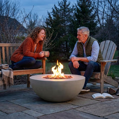 Two people talking beside the 15-inch-tall Modeno Roca concrete fire bowl at dusk