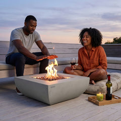 A couple relaxing around the 14-inch-tall Modeno Westport fire pit table at dusk