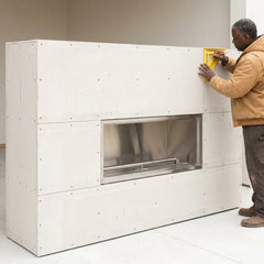 Installer beside the Outdoor Greatroom 60 inch ready-to-finish fireplace enclosure (252 lbs) before cladding